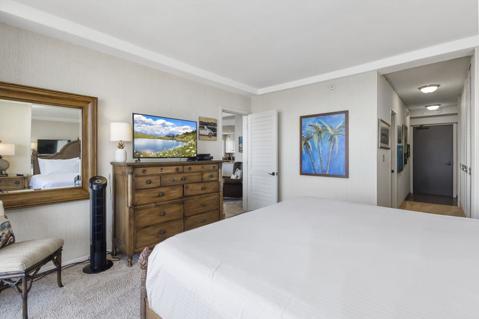 Sink into crisp linens and unwind in your private retreat, where tropical artwork, a large flatscreen TV, and elegant wood furnishings create a calming, coastal-inspired ambiance.