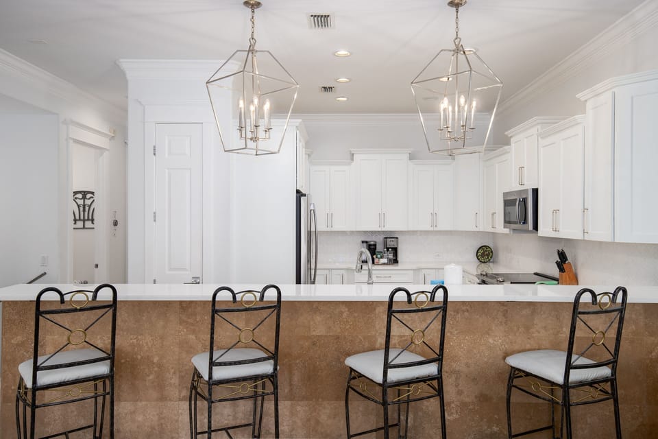 Gather around this elegant kitchen island where crisp white cabinetry meets warm stone, perfect for morning coffee or evening conversations.