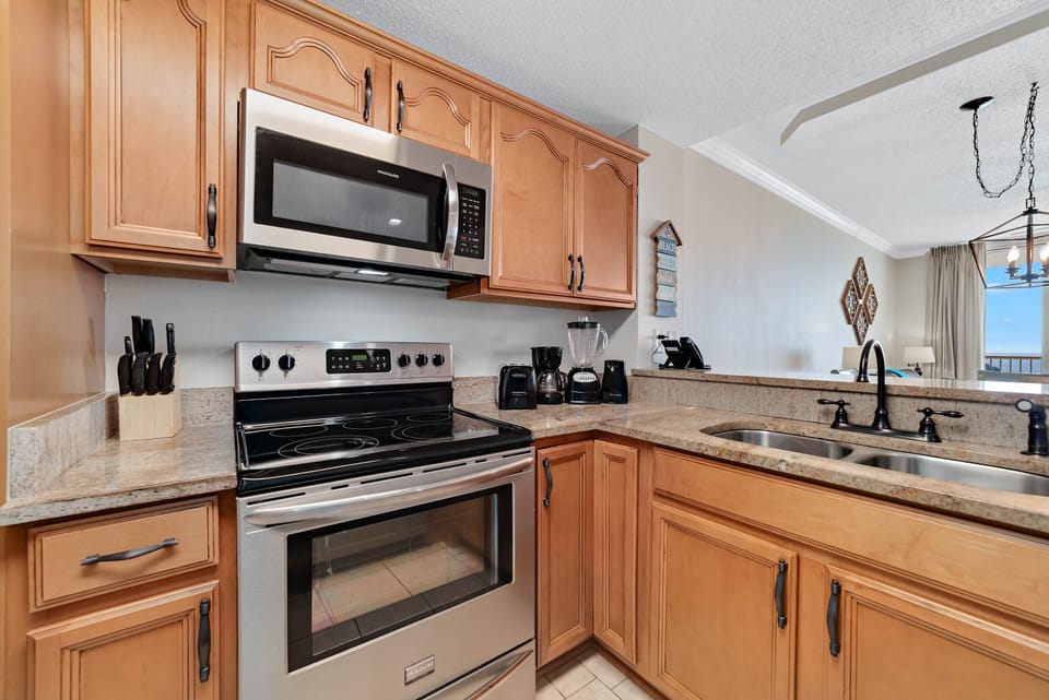 This fully functional kitchen boasts stainless steel appliances, sleek countertops, a decorative backsplash, and ample cabinet storage, ideal for everyday cooking and entertaining.