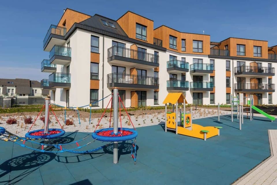 A children’s playground with vibrant equipment surrounded by modern residential buildings.

