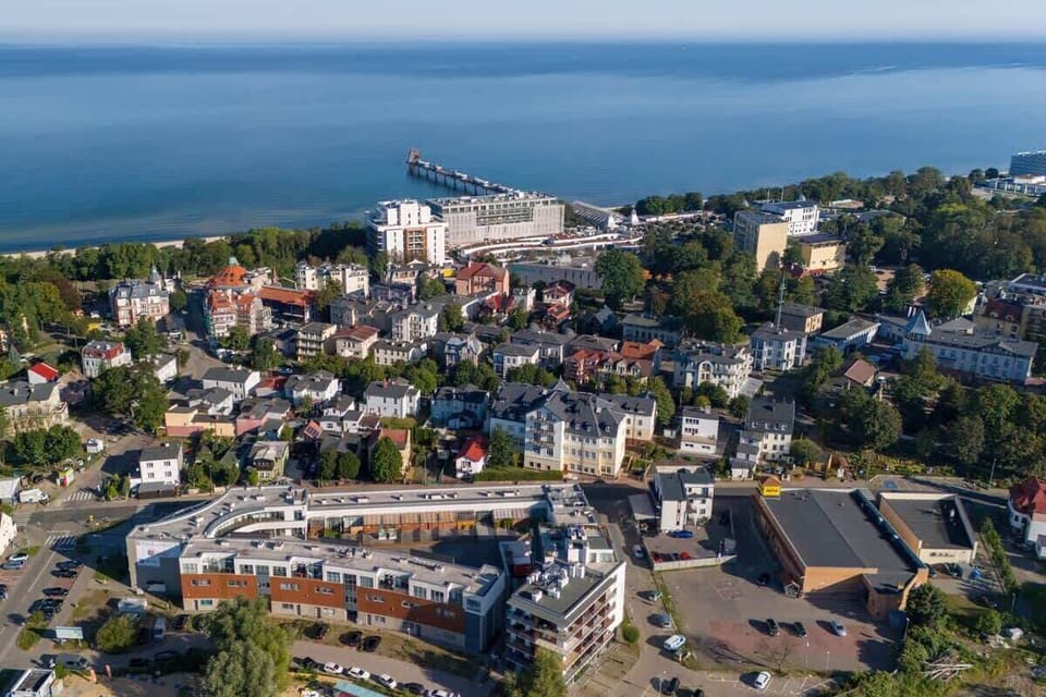 A view of the coastal area with modern residential buildings, open spaces, and the sea in the background.
