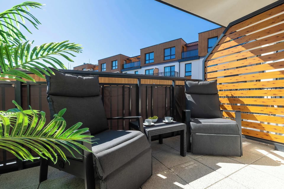 A cozy outdoor patio with seating, plants, and a wooden privacy wall.