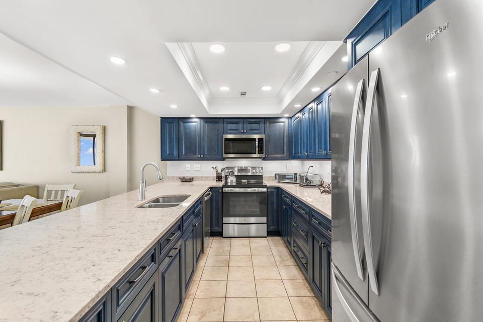Your fully equipped kitchen features elegant navy cabinetry, gleaming granite counters, and premium stainless steel appliances—perfect for preparing memorable meals during your stay.