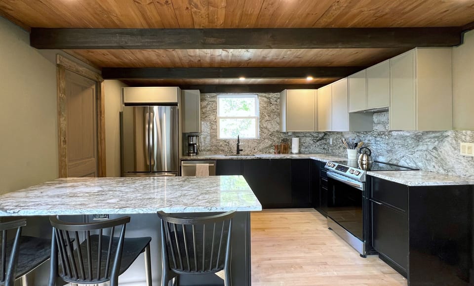 The new spacious kitchen is open to the living area, includes a granite countertop and full-height backsplash, ample storage, and a 3-seat peninsula.