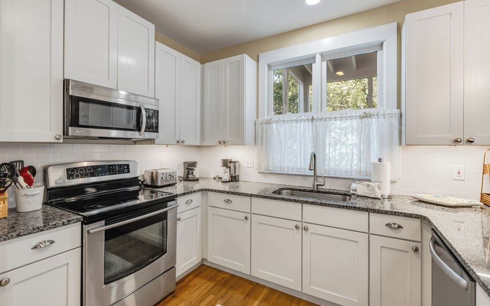 Your fully equipped kitchen awaits with granite counters, stainless appliances, and charming garden views through the window.
