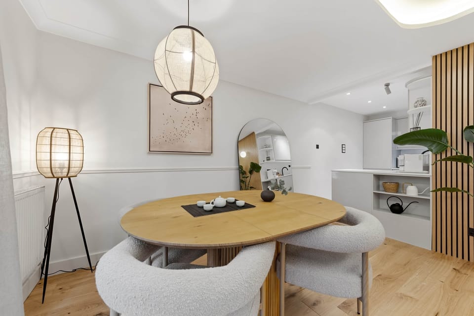 Modern dining nook with sculptural lighting, curved table and soft neutral tones