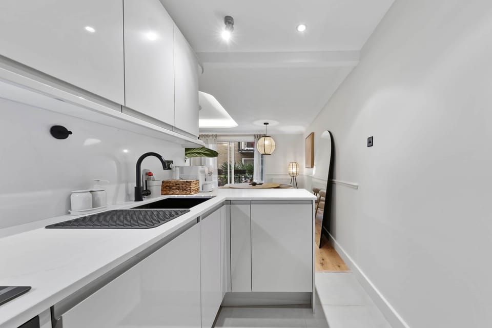 Slim galley kitchen with continuous countertop, matte black tap, glossy backsplash and efficient lay