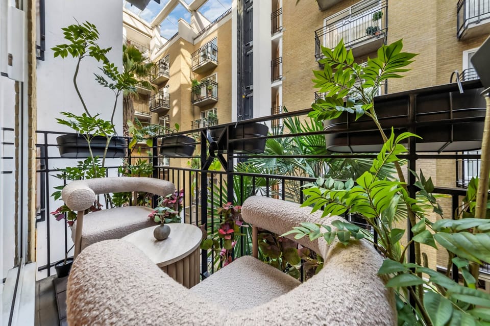 Leafy balcony with cozy seating, small table and courtyard views, creating a calm, inviting outdoor 