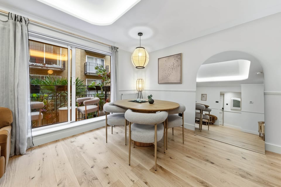 Cozy dining nook besides wide sliding doors, featuring a rounded table plush chairs, soft drapery an