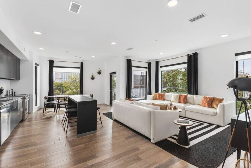 Open floor plan from the kitchen to living room, equipped with new furnishings, plenty of natural light, and the balcony overlooking the Cumberland river.