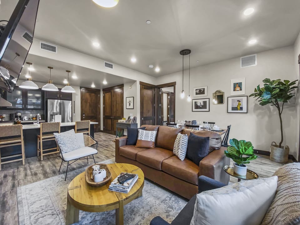 Unwind in this bright, modern sanctuary featuring a warm stone fireplace, a large smart TV, and plush leather seating. A serene and cozy hub perfect for relaxing after adventure.