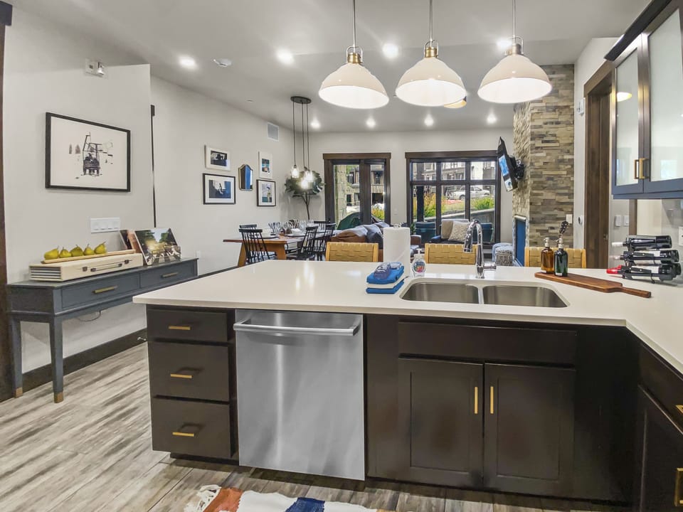 Cook with ease in this bright, modern kitchen featuring premium stainless steel appliances, sleek dark cabinetry, and expansive white countertops—an inviting hub for group meals and morning coffee.