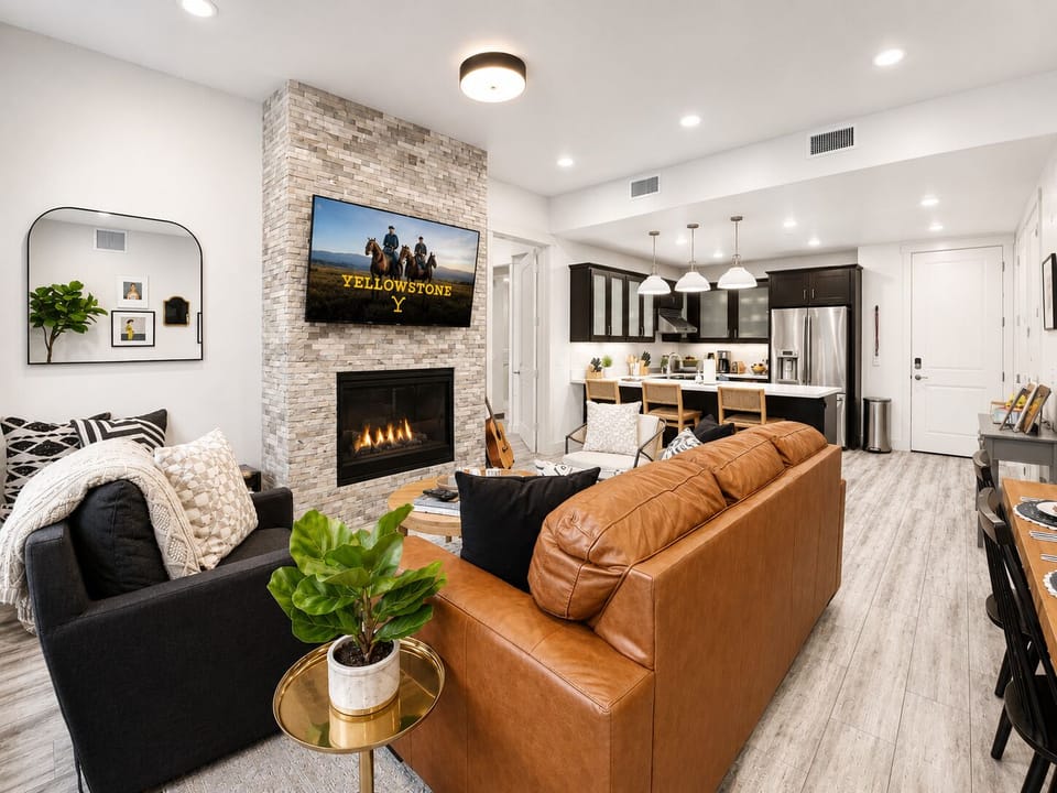 Sink into plush leather seating in your open-concept living space, where a stone fireplace and large TV set the scene for cozy evenings. The modern kitchen awaits your culinary adventures.