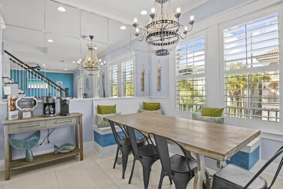 Gather around this spacious dining table where coastal chandeliers and turquoise accents create your perfect breakfast spot.
