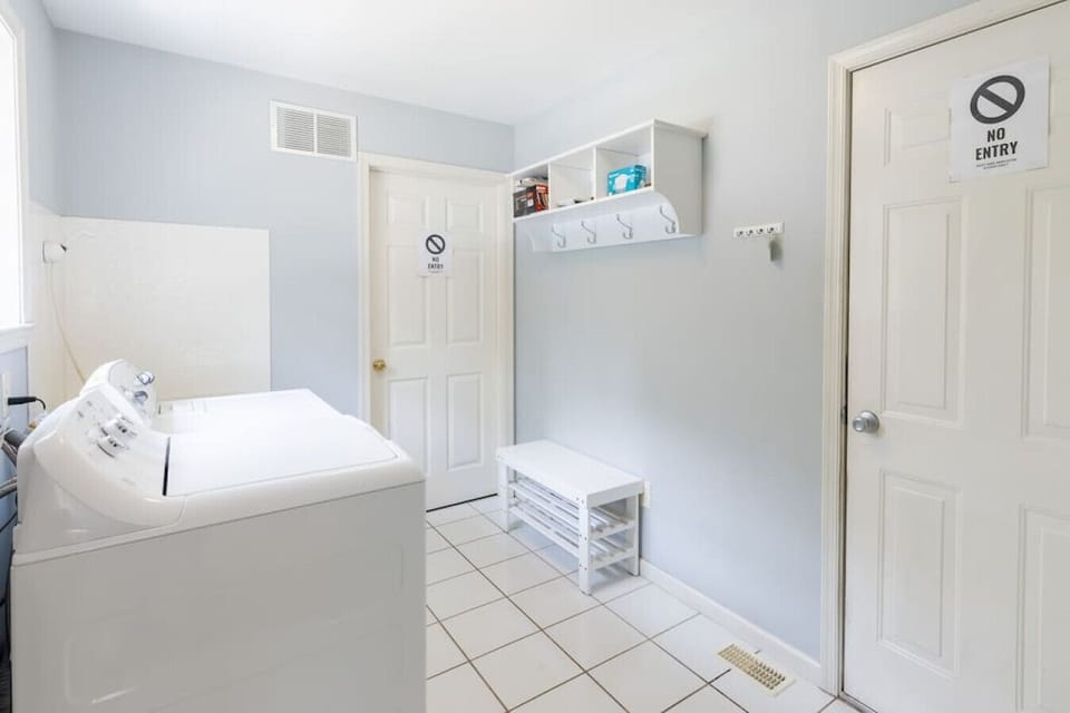 Clean and convenient laundry area featuring full-size washer, dryer, and organized shelving, ideal for families or long-term guests