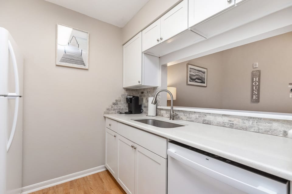 Your bright galley kitchen features gleaming white cabinets, marble countertops, and modern appliances for all your culinary adventures.