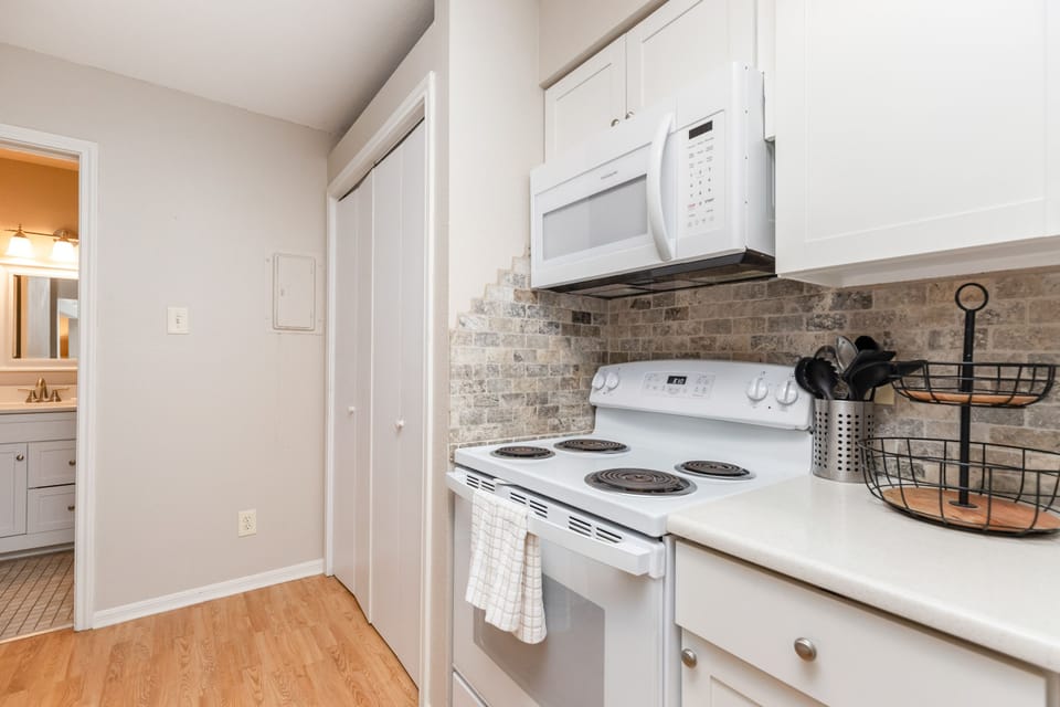 Your fully equipped kitchen awaits with crisp white cabinets, stone-tile backsplash, and modern appliances for easy meal preparation.