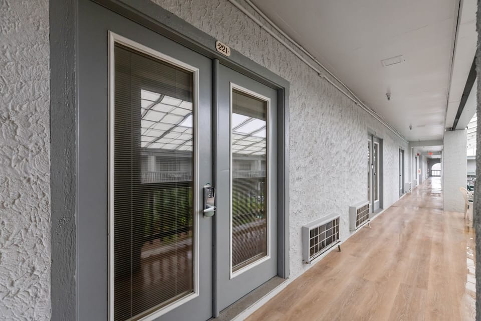 Bright corridors with numbered rooms lead you to comfortable accommodations, each featuring modern gray doors and natural light from skylights above.