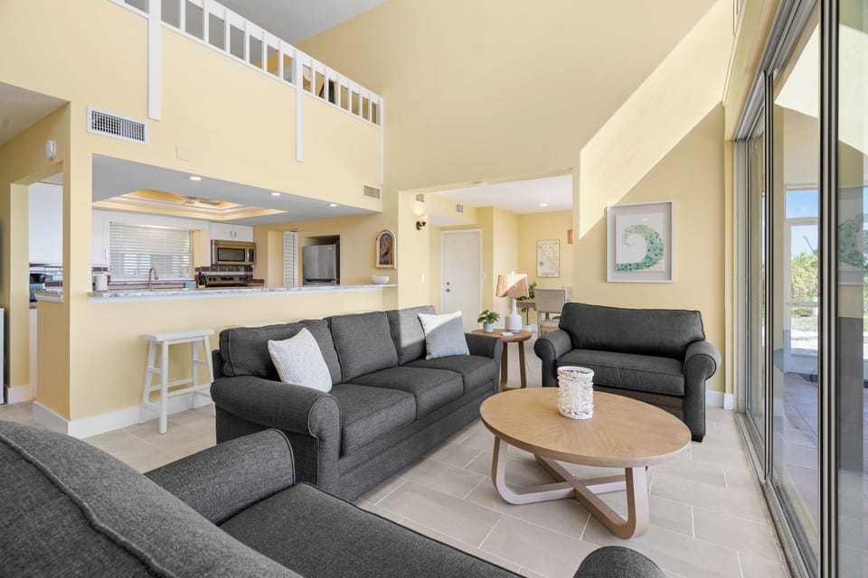 Relax in your spacious living room with comfortable seating, open kitchen views, and bright natural light streaming through sliding doors.