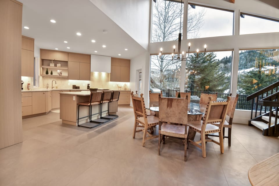 Bright open kitchen and dining area with high ceilings and panoramic windows for mountain views.