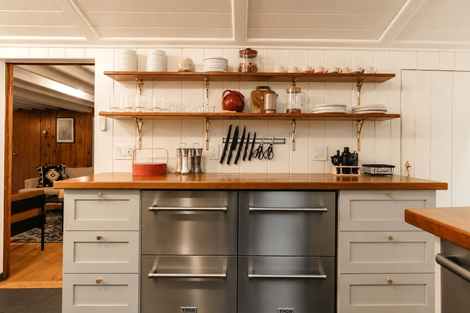Reach for glasses and plates off the open shelves, or grab a knife from the rack for prep work. The drawer fridge and freezer under the counter keep drinks and food cold, with salt, pepper, and a coffee press within reach.