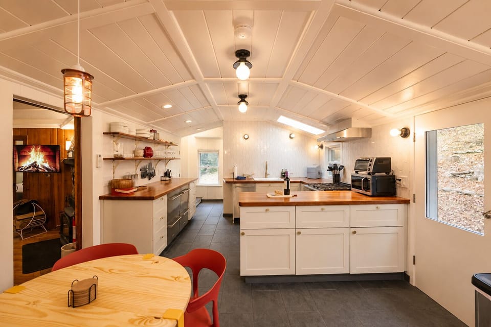 Cook up a meal on the range and plate it at the counter, then eat at the pine table with the red chairs. Shelves hold the dishes and mugs you need, plus a toaster oven and microwave for quick snacks or late night bites.