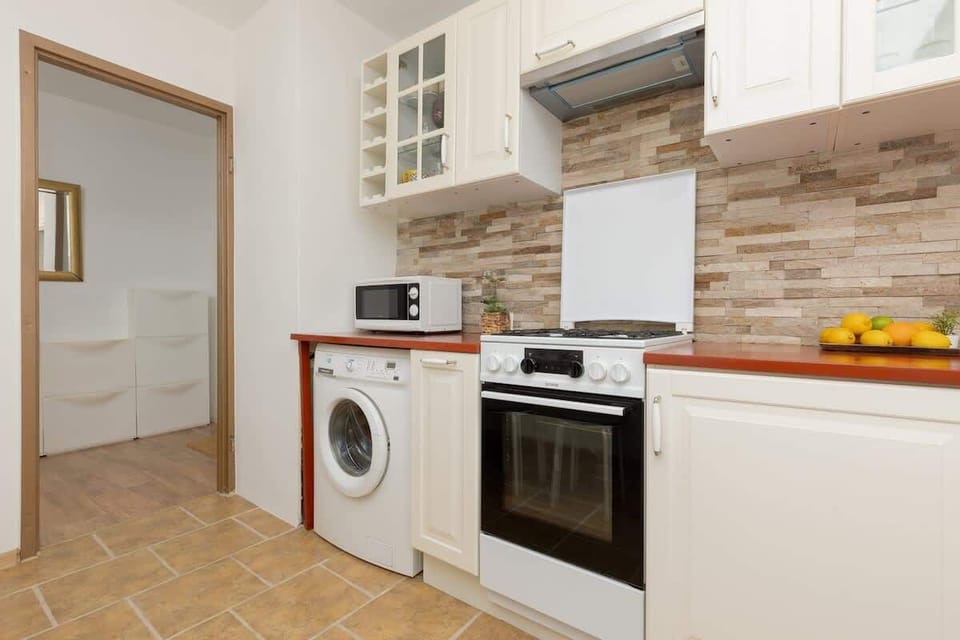 A well-equipped kitchen featuring a built-in oven, microwave, and a brick-style backsplash.
