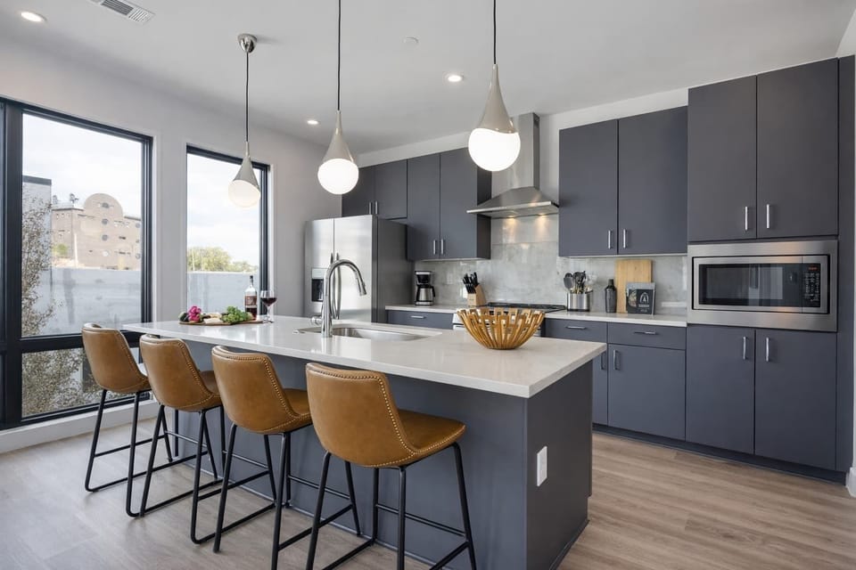 Fully equipped kitchen with stainless steel appliances, basic cooking essentials, toaster, coffee machine, and kitchen island seating.