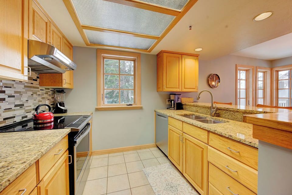Your fully equipped kitchen welcomes you with warm wood cabinets, granite countertops, and natural light streaming through garden windows.