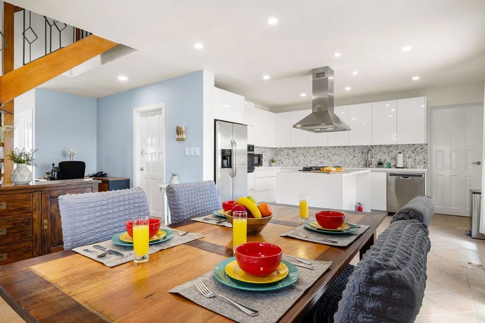 Your open-plan kitchen and dining area combines bright white cabinetry, modern appliances, and a warm wood table set for breakfast—perfect for gathering with loved ones over morning meals.