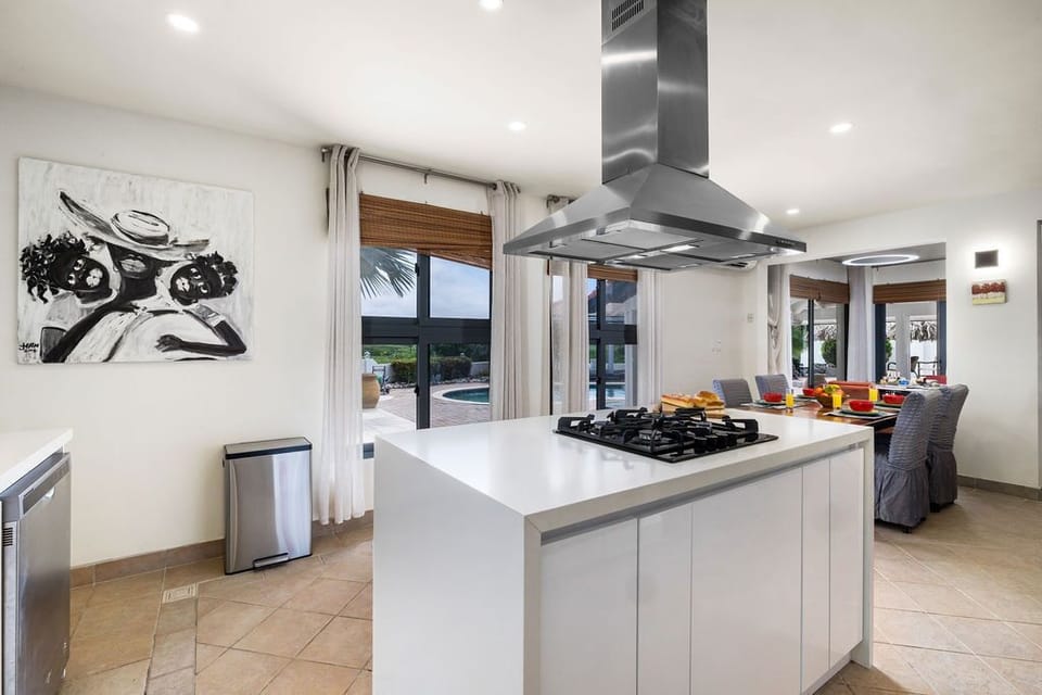 The sleek kitchen island flows seamlessly into your open dining area, where pool views through large glass doors frame every meal. Modern appliances and ample counter space make cooking effortless.
