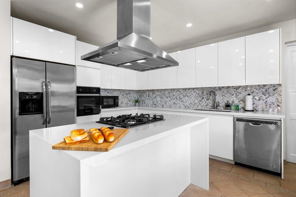 Bright modern kitchen featuring a gas stove, sleek stainless appliances, and elegant marble backsplash—perfect for preparing your favorite meals during your stay.