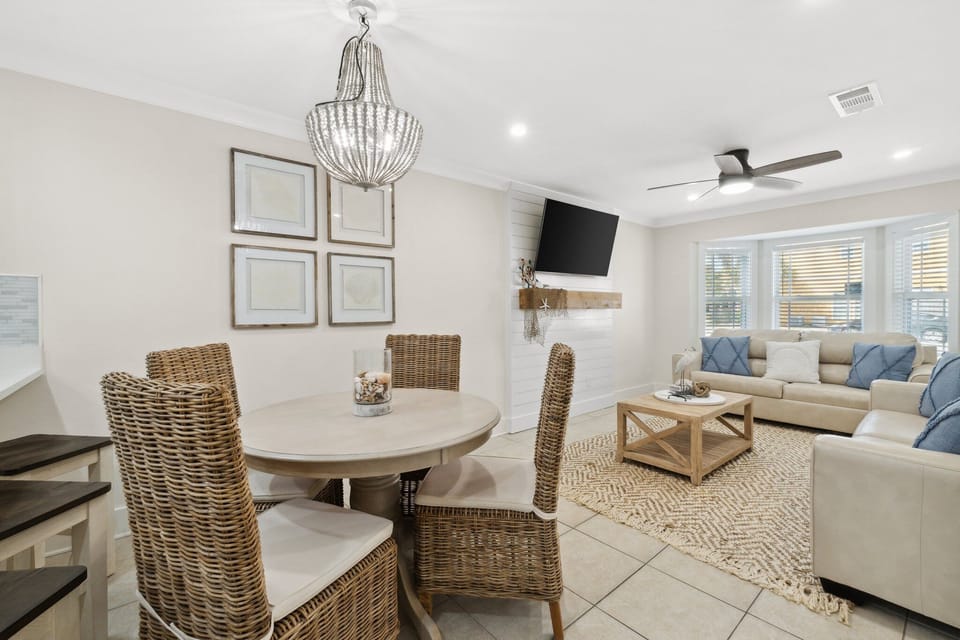 open living and dining area with woven chairs and a mounted television