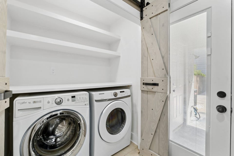 Laundry area with modern washer and dryer behind a rustic sliding barn door.