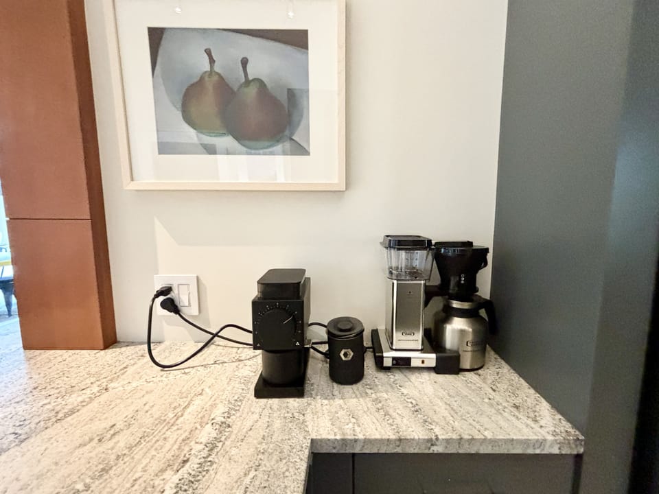A kitchen counter with a picture of pears on the wall.