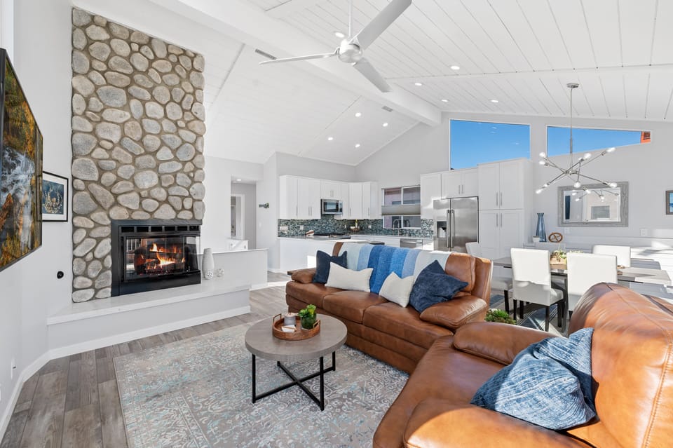 Second floor living room area, fireplace, and ceiling fan to kitchen area