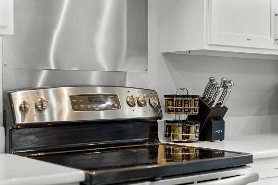 Cook with ease in this modern kitchen with a stainless stove, spices & knives.