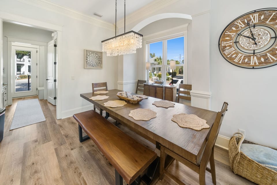 Gather around this elegant dining table where memorable meals unfold under the sparkling chandelier, with natural light streaming through arched windows.
