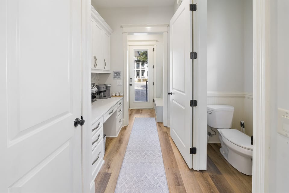 Your bright hallway connects everything seamlessly—modern kitchenette on the left, powder room on the right, and charming entrance ahead.