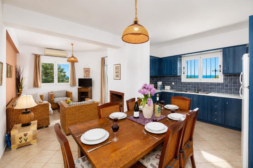 Open-plan living room with sofa, dining area, kitchen, ornamental fireplace, A/C, WiFi internet, and satellite TV
