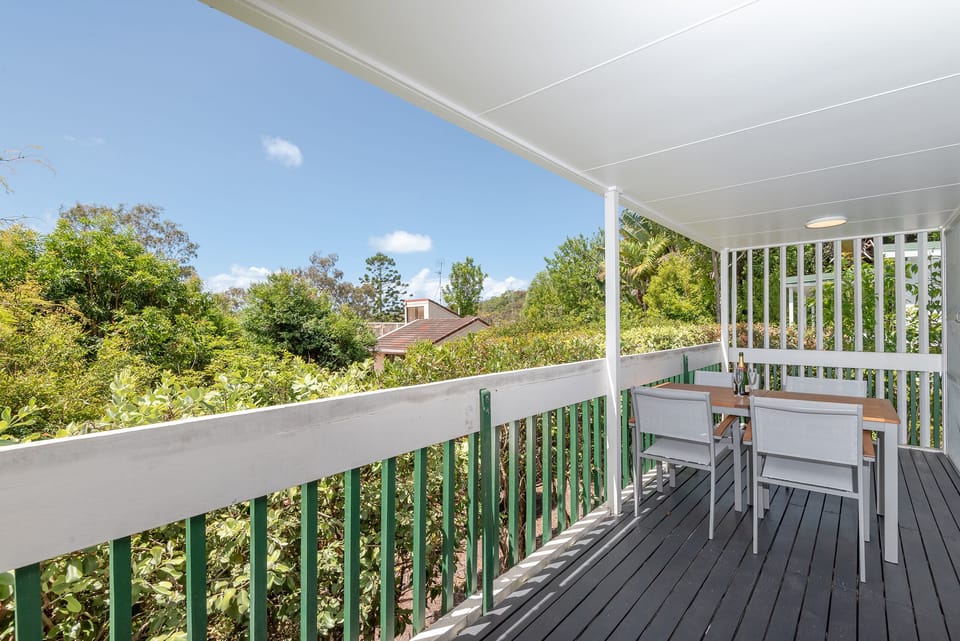 Private balcony dining with leafy surrounds and flow from open-plan living area.