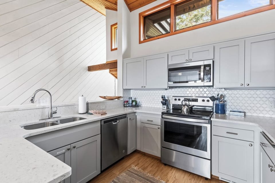 Fully equipped kitchen with stainless appliances, stone counters, and elevated breakfast bar seating.
