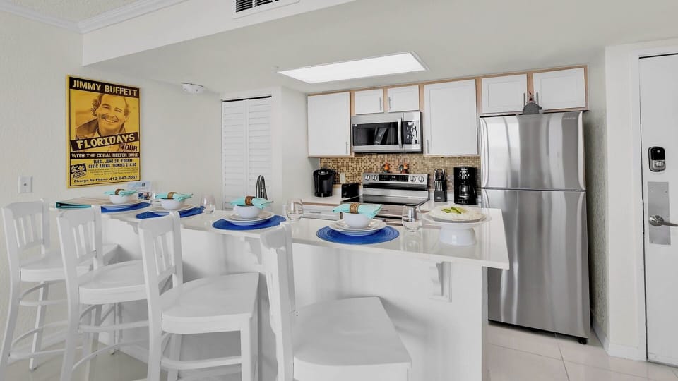 Gather around this bright kitchen with a breakfast bar styled for beachy meals. Enjoy full appliances, coastal decor, and a welcoming space where you can cook and dine together.