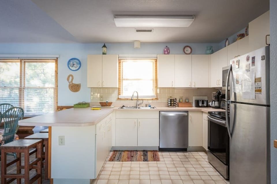 Top Level Fully Equipped Kitchen with a Refrigerator, Stove, Oven, Microwave, Dishwasher, Coffee Maker, Toaster, and Breakfast Bar Seating, Plus Natural Light from Nearby Windows