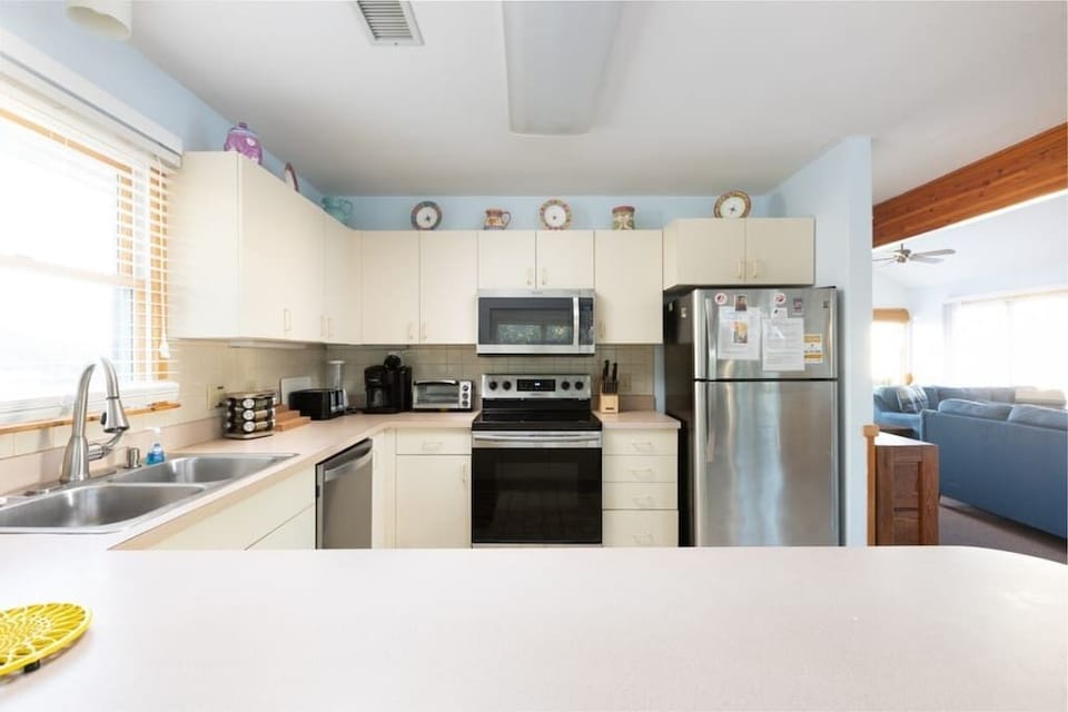 Top Level Fully Equipped Kitchen with a Refrigerator, Stove, Oven, Microwave, Dishwasher, Coffee Maker, Toaster, and Breakfast Bar Seating, Plus Natural Light from Nearby Windows