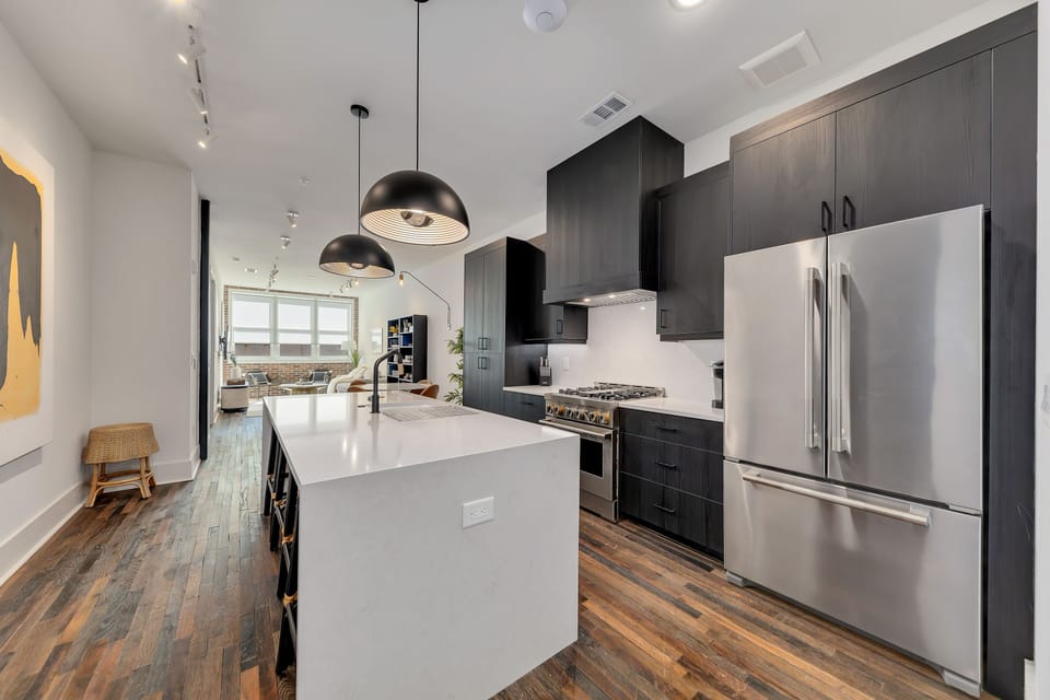 Sleek kitchen w/ large island, dark cabinetry & stainless steel appliances
