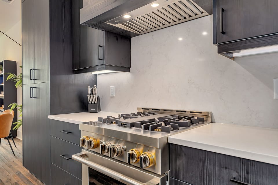 Gourmet gas range w/ modern hood & clean backsplash for easy cooking