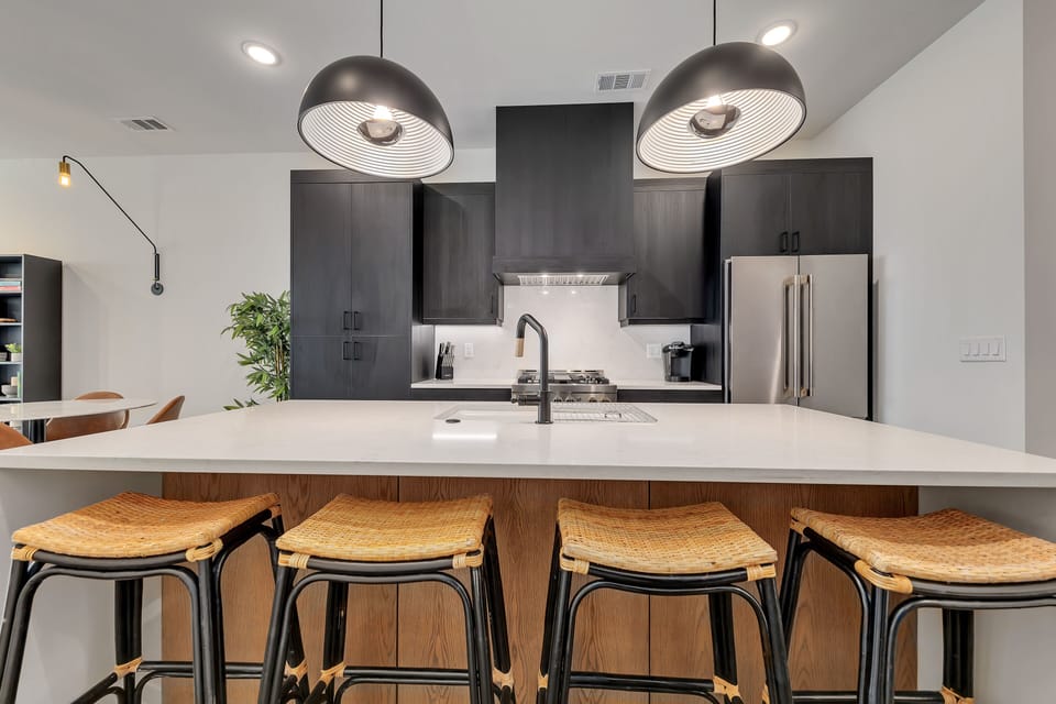 Kitchen island seating w/ pendant lights, woven stools & sleek finishes
