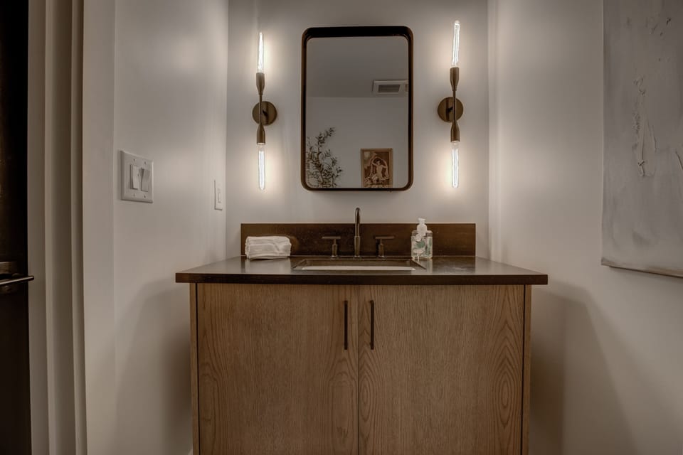 Modern vanity w/ warm wood cabinetry, sleek sink & soft lighting