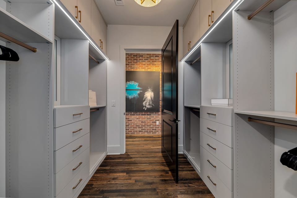 Spacious closet lined w/ storage, hanging space & warm wood flooring